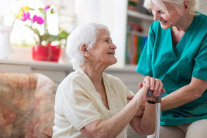 Elderly woman smiling up at her caregiver