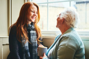 Young caregiver talks to senior woman about at-home care solutions.