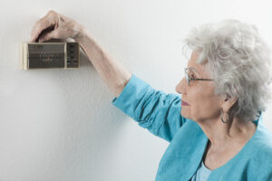older-woman-adjusting-thermostat