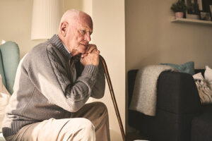 elder man leaning on his cane while sitting down