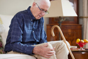 A man rubs his sore knee and wonders how long his joint replacement surgery will take, a key question to ask your doctor before a procedure.